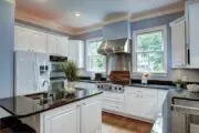 light blue kitchen with white cabinets, navy counters and stainless steel appliances