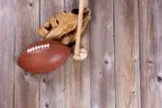Football, baseball glove and baseball bat on wood floor