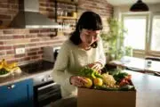 Woman in a kitchen removing vegetables from a bag - sustainable home