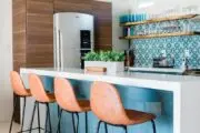 Popular color trend dopamine decor seen here with pink bar stools, white island and white and blue wallpaper