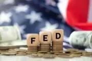 Blocks spelling "FED" stacked on top of coins with an American flag in the background -federal rates hold steady again
