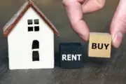 White miniature house with blocks reading "rent" and "buy"