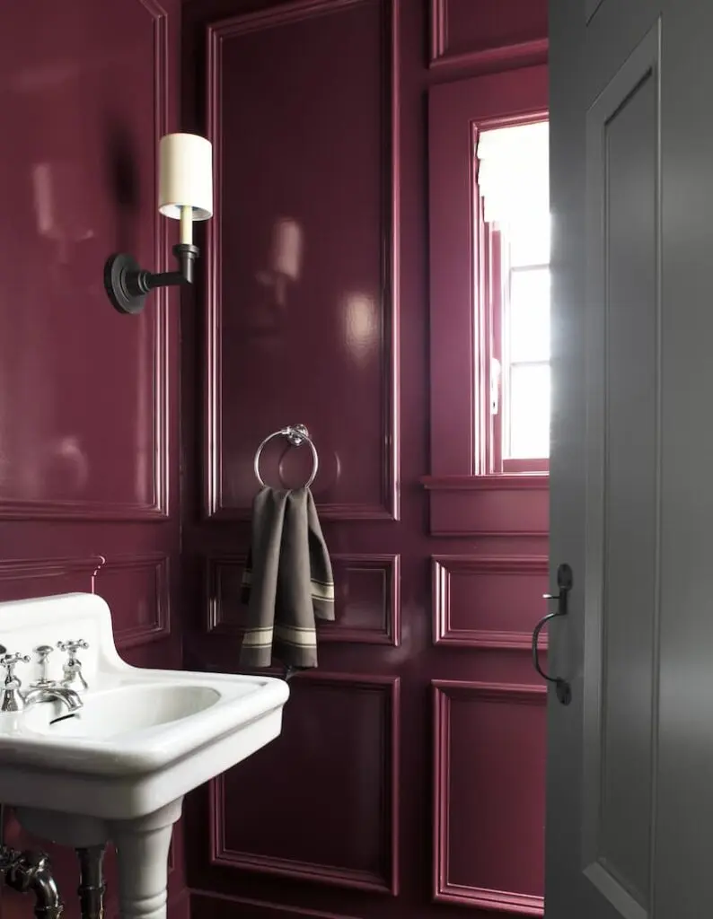 A powder room is painted in all burgandy, with a white sink.
