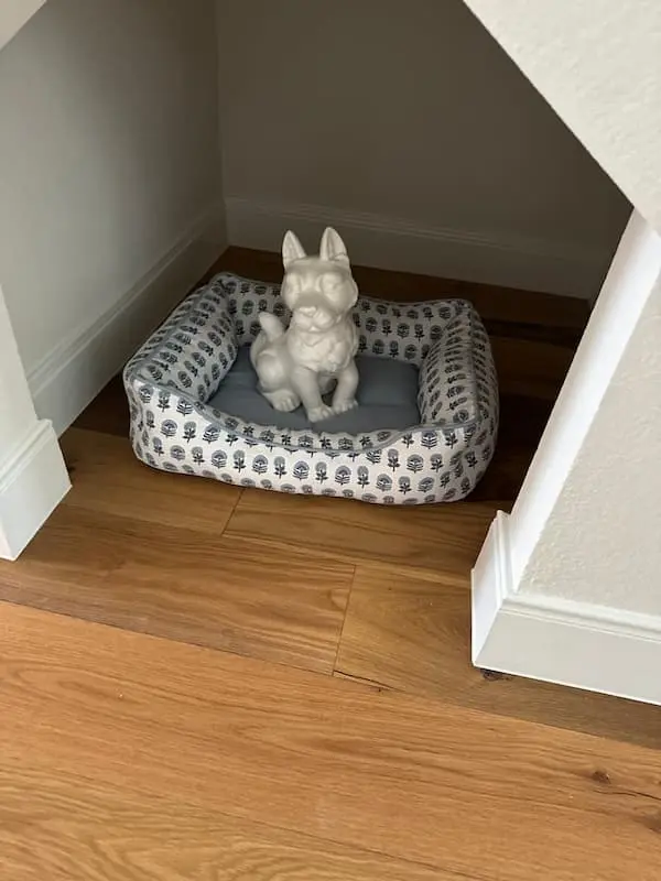 Dog bed space under a stairwell with a ceramic dog