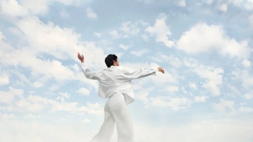 person dancing against a cloudy sky showing Pantone's Color of the Year for 2026, Cloud Dancer